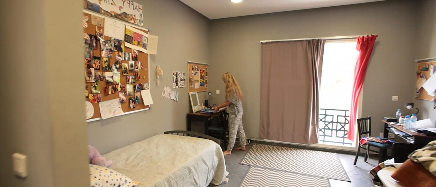 A student near the balcony doors in her modern dorm room within the U N E Tangier residences