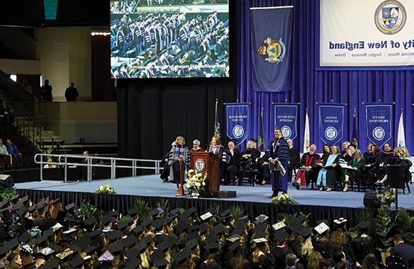 在2022年东北大学毕业典礼上，人们坐在舞台上听演讲者讲话