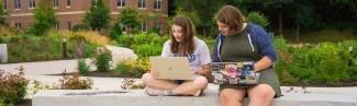 两个学生坐在比德福德校园外的笔记本电脑上